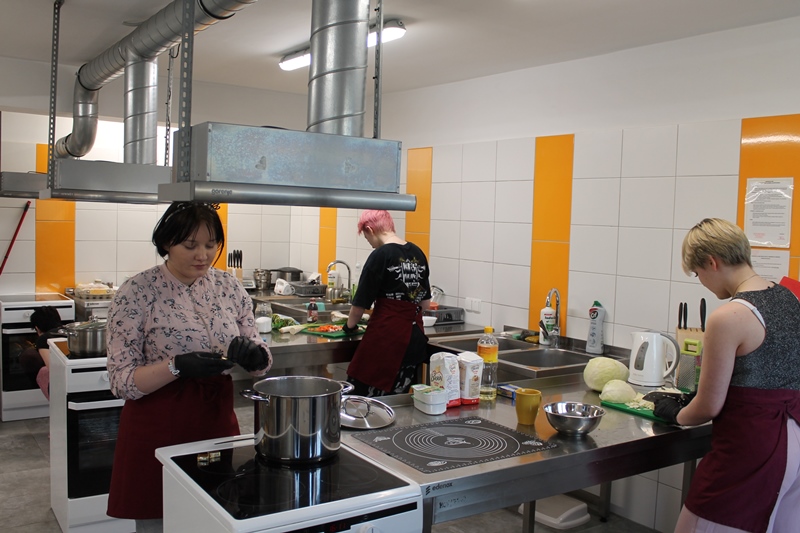Uczestniczki w kuchni przygotowują potrawy.