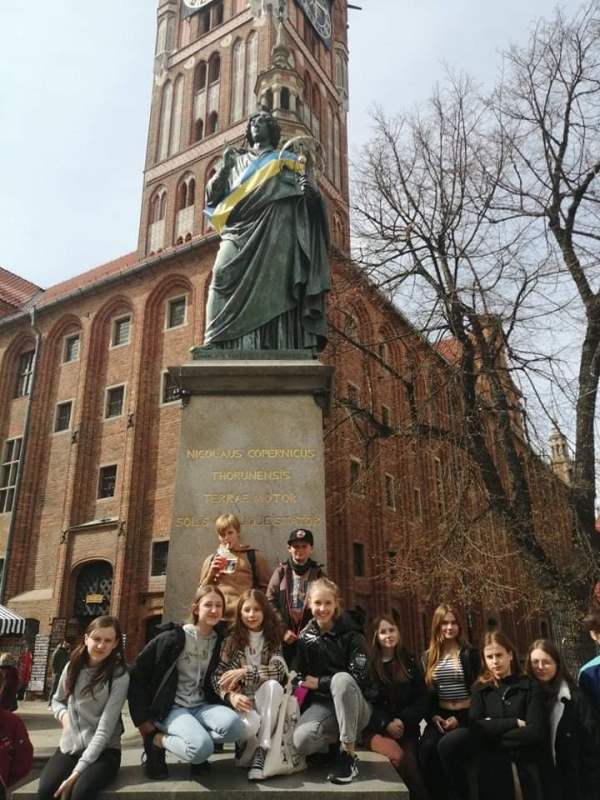 Grupa dzieci pod pomnikiem M. Kopernika w Toruniu.