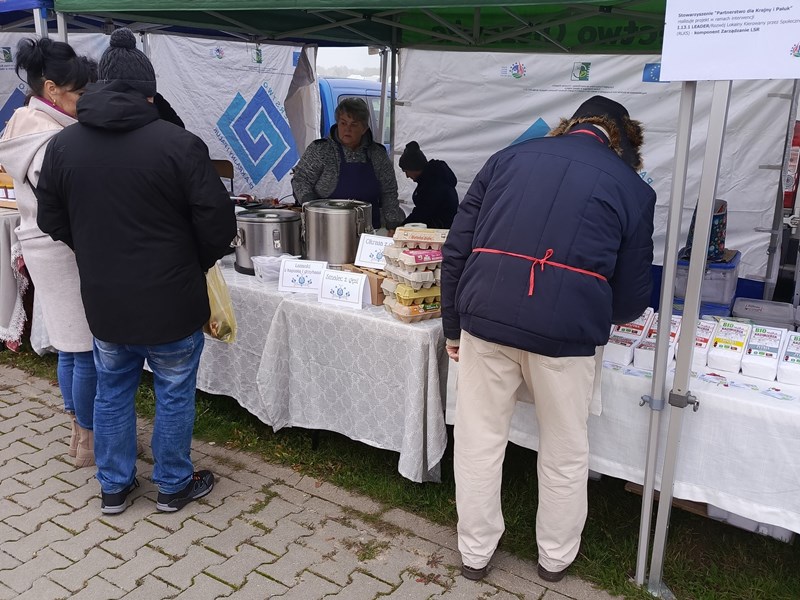 Stoisko LGD: pod namiotem stoi i stół, a na nim leży obrus. Na obrusie prezentowane są paczki z mąką.